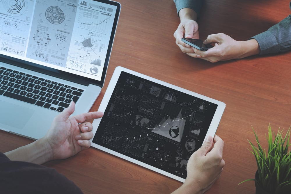 top view of two colleagues discussing data with new modern computer laptop and pro digital tablet with digital business strategy layer effect on wooden desk as concept